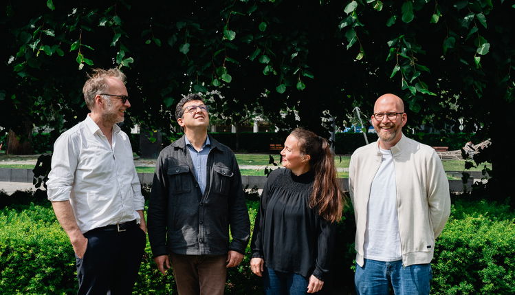 Fire musikere står foran en hekk